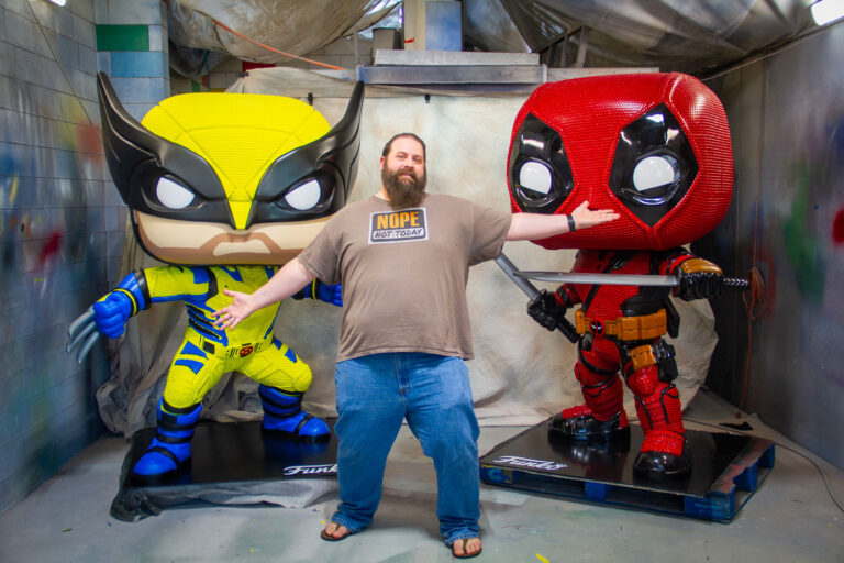 Deadpool and Wolverine statues with one of the WhiteClouds designers